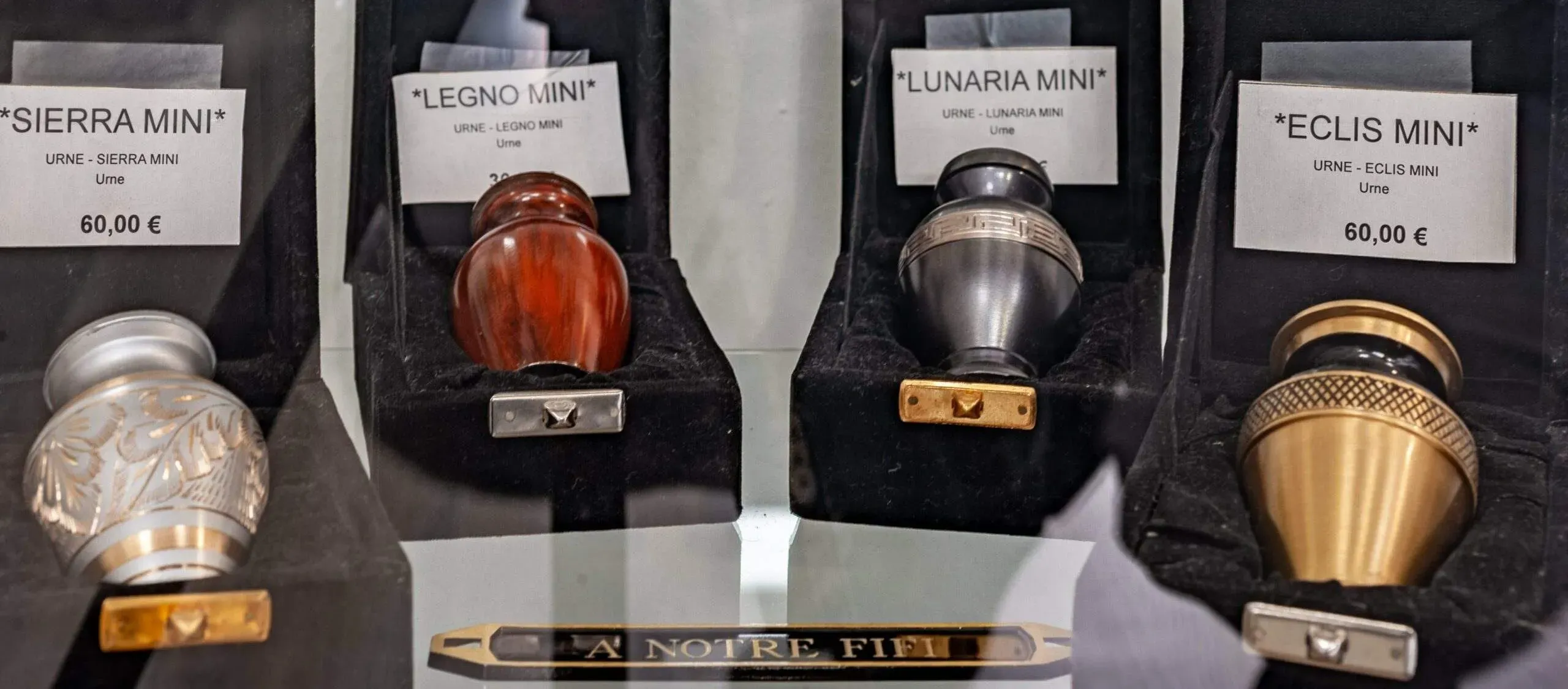 Mini urnes cinéraires personnalisées exposées en vitrine d'agence.