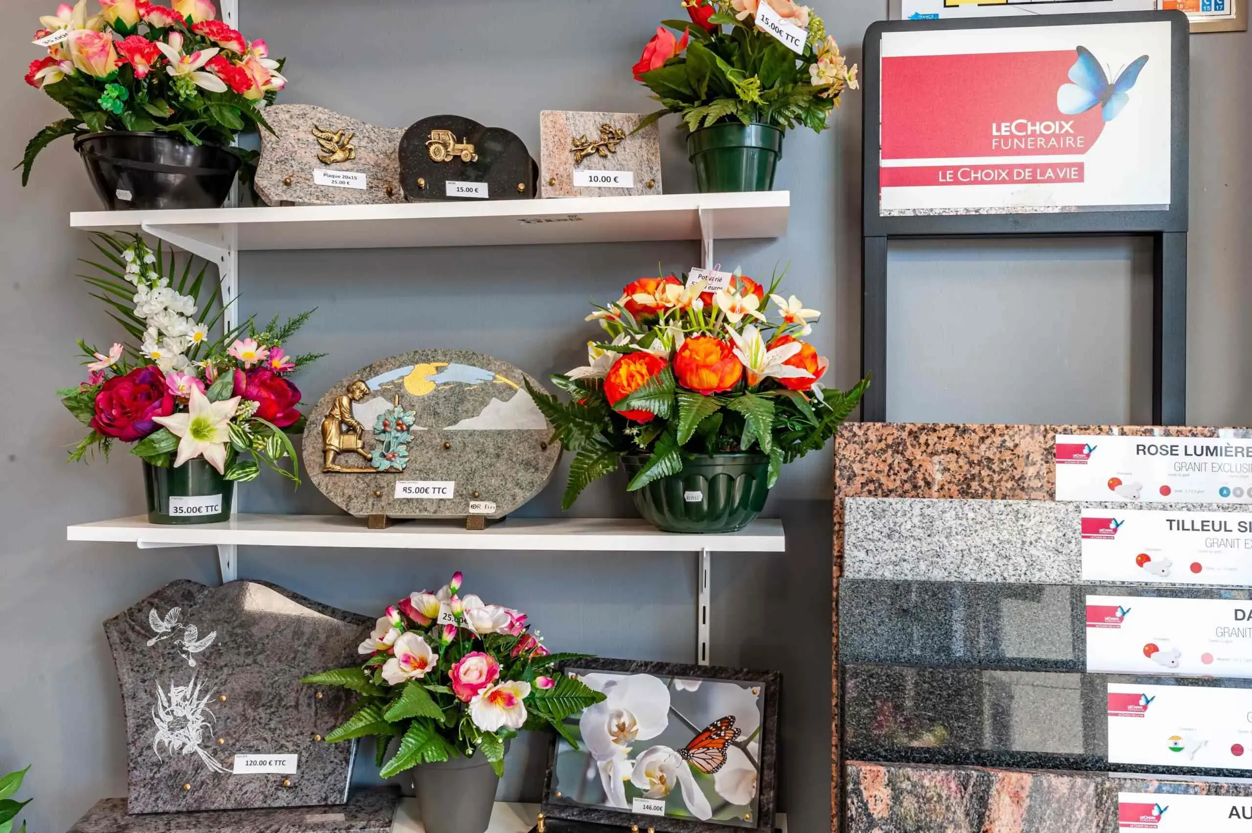 Plaques funéraires, compositions florales et échantillons de granit exposés en agence.